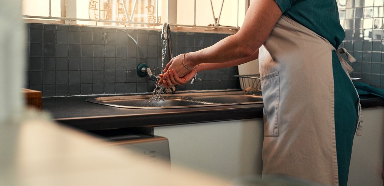 امرأة تغسل يديها في المطبخ
