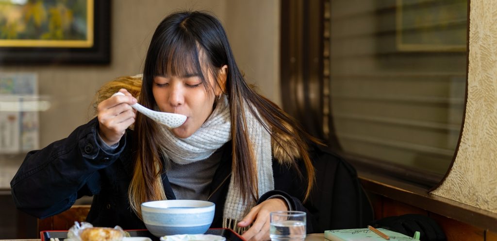 امرأة تأكل الحساء الساخن